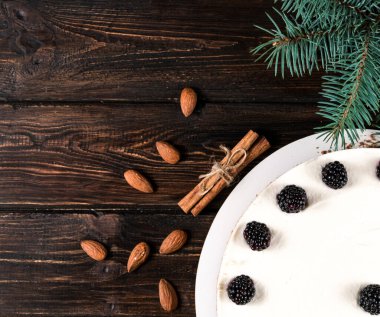 Böğürtlenli kremalı pasta, çikolatalı krema ve donmuş böğürtlenler beyaz bir tabağın üstünde, ahşap bir arka planda..