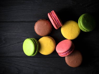 Siyah ahşap arka planda renkli badem kurabiyeleri.