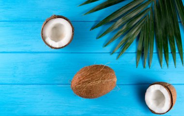 Hindistan cevizi ve palmiye yaprakları mavi ahşap arka planda