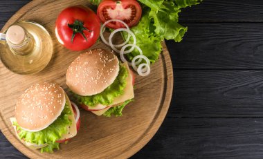 Eski bir mutfak tahtasına iki hamburger ve saksı.