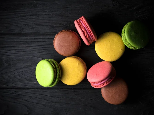 Siyah ahşap arka planda renkli badem kurabiyeleri.