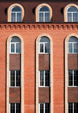 Bir sürü penceresi olan yüksek katlı beton binanın dikey görüntüsü.