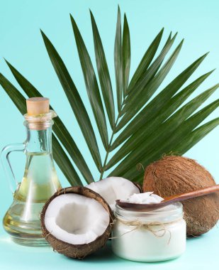 Hindistancevizi ve yeşil palmiye yaprağıyla mavi arka planda hindistan cevizi palmiyesi yağı..