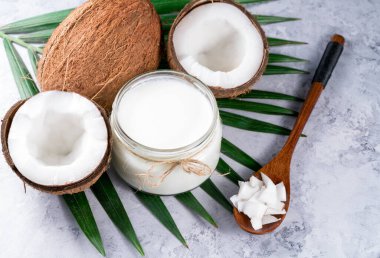 Hindistan cevizi yağı ve olgun hindistan cevizi, tropikal palmiye ve canavar yaprakları..