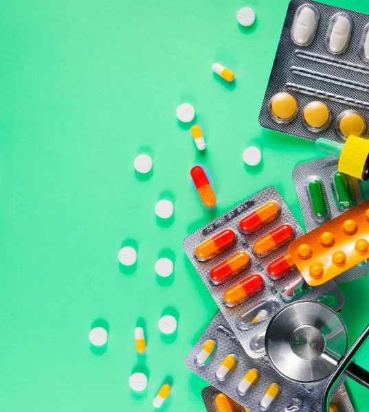 緑の背景にカプセルや錠剤とカラフルな錠剤 — ストック写真