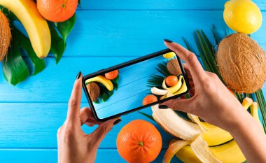  Farklı tropik olgun meyveler ve mavi bir arka planda yer alan palmiye yaprağı çerçevesi.