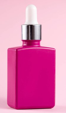 Kozmetik ahududu şişesi pembe arka planda