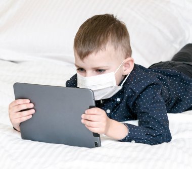 Çocuk bir kanepede dizüstü bilgisayarla yatıyor.