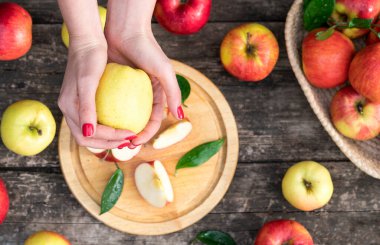 Kadın ellerinde tutulan bir elma. Elma arkaplanı bulanık ahşap masa