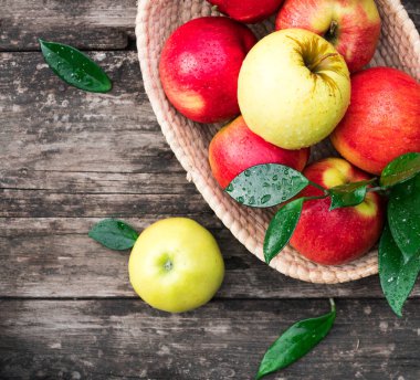 Tahta bir arka planda sepetteki olgun elmalar.