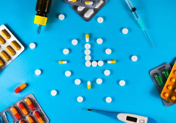 青の背景に時計の形で配置されたさまざまな薬のグループ 薬局で時間だ 薬の時間 — ストック写真