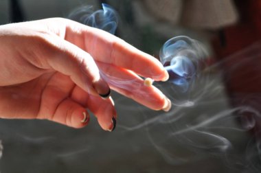 Sigara içen Sigara İçilmeyen elinde tutuyor. Çok duman