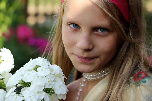 Belle petite fille blonde aux cheveux longs sentant la fleur — Photo