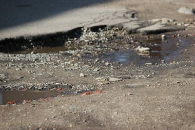 Asfalt yolda su taşları ve su birikintileri ile büyük çukurlar