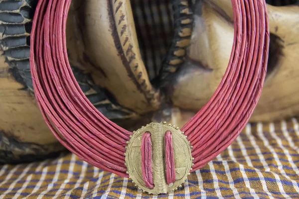 African tribal necklace with African mask in background, private collection