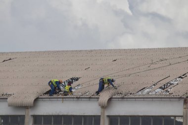 Mozambik ve Zimbabve'de Aftermath Cyclone Idai ve Cyclone Kenneth, insanlar hasarlı çatı sabitleme 