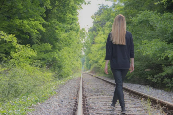 Young girl taking a walk at railway in forest with beautiful nature around