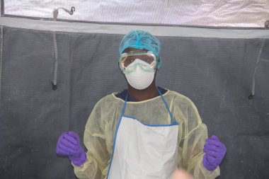 Koruyucu ekipman, önlük, eldiven, google ve maske takan bir doktor. Hem onu hem de seni koruyordu.