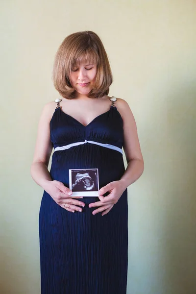 Schwangere streichelt ihren Bauch über grüne Wand — Stockfoto