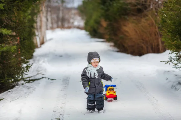 Piccolo ragazzo a piedi con il suo camion giocattolo discarica — Foto Stock