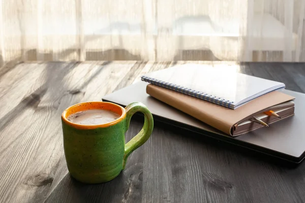 Ranní šálek kávy, notebooku a notebook v okolí. — Stock fotografie