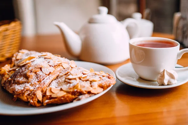 Primer plano de la taza de té, tetera y croissant en la mesa en la cafetería — Foto de Stock