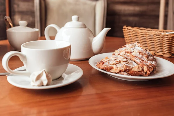 Copa blanca, tetera y croissant en la mesa en la cafetería — Foto de Stock