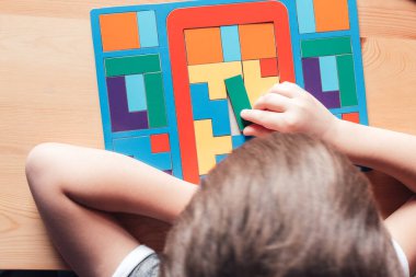 Çocuk masaya oturur ve bulmacaları çözer.