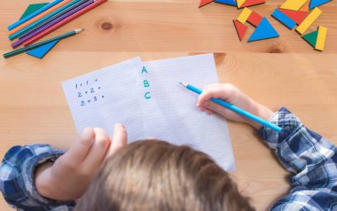 Yukarıdan çocuğa bak. Masanın başına otur ve ders yap.