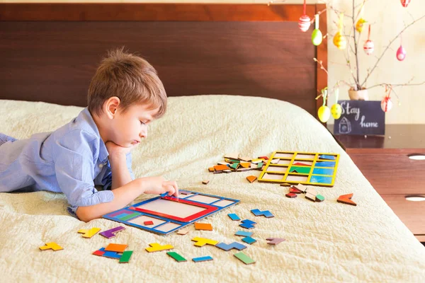 Tråkig pojke samlar pussel sittande på sängen — Stockfoto