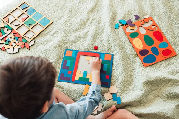 Anak yang bahagia duduk di tempat tidur dan meletakkan teka-teki — Stok Foto