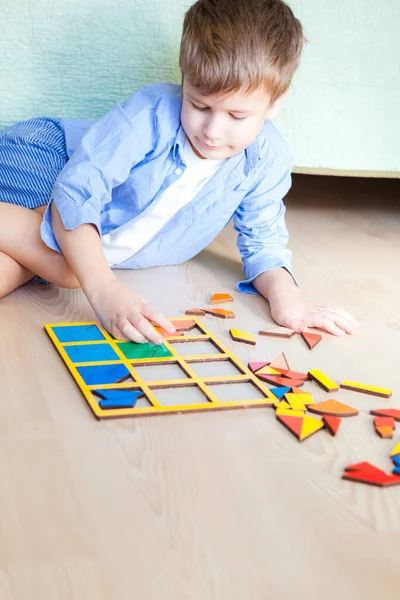 De gelukkige jongen zit op de vloer en legt puzzels — Stockfoto