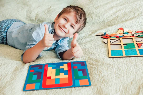 Щасливий хлопчик сидить на ліжку і кладе головоломки — стокове фото