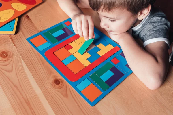 Glad pojke sitter i närheten skrivbord och lägger pussel — Stockfoto