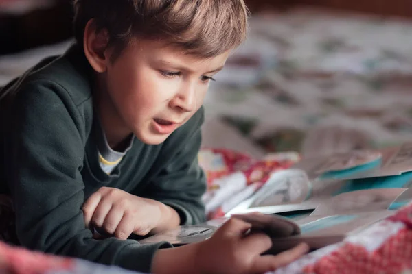 Niño acostado en el sofá y leyendo un libro — Foto de Stock