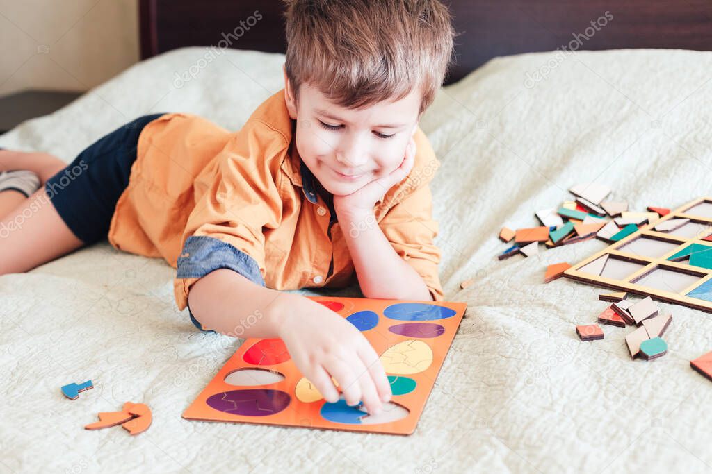 Child boy collects puzzle in the form of eggs