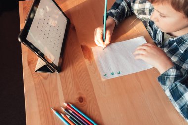 Modern çocuk evde çalışmak ve çizim yapmak için uygulamayı tablet üzerinde kullanır