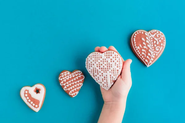 Pepparkakor kakor på blå bakgrund. Barnens hand håller i en pepparkaka — Stockfoto