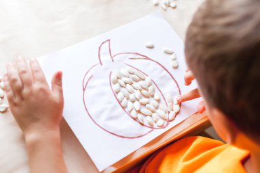 Tohumlardan balkabağı yapan çocuk, Cadılar Bayramı konsepti, üst görünüm.