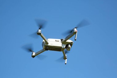 Beyaz dron mavi gökyüzünde uçan