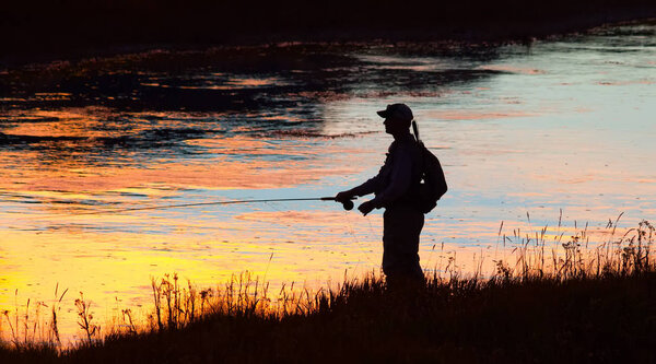 man fishing in Yellowstone national park  at sunset 