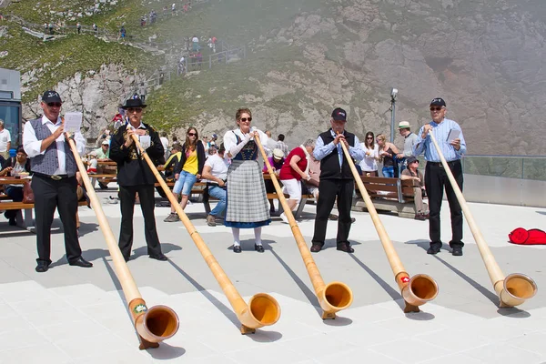 MOUNT PILATUS - JULY 13: Unidentified people playing traditional swiss music with alphorns on July 13, 2013 on the top of Pilatus, Switzerland. Alphorn is traditional music instrument of Switzerland.