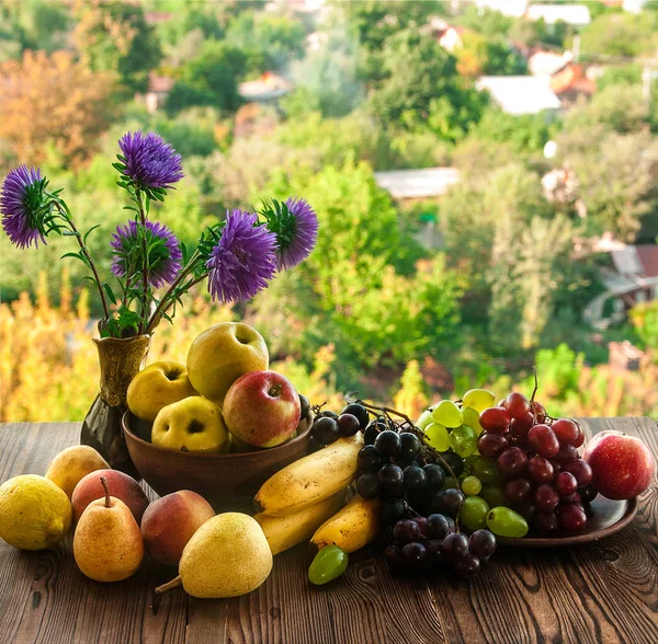 Спелые фрукты и цветы на деревянном столе — стоковое фото
