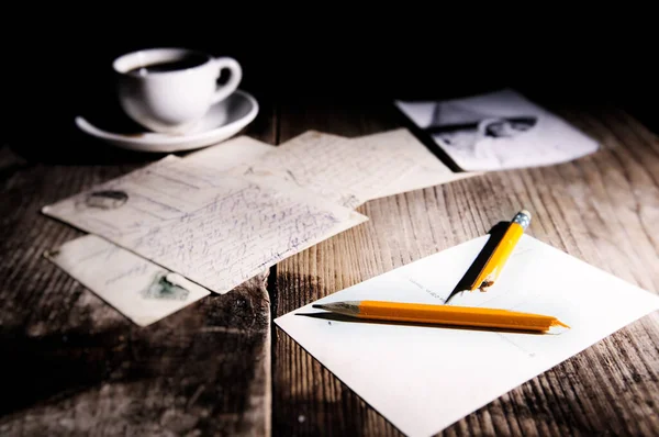 Gamla vykort, kaffekopp och trasig penna på ett träbord Stockbild