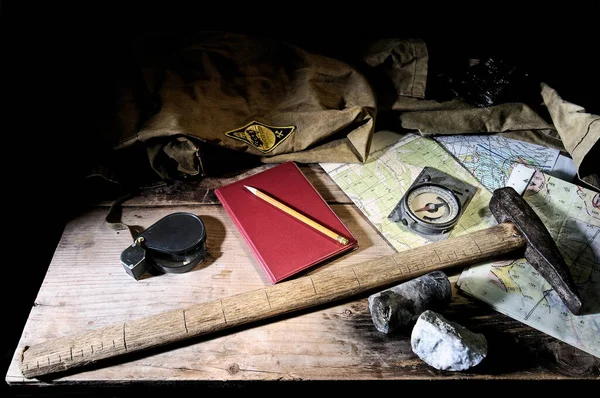 Ferramentas geológicas - mapas, martelo, bloco de notas, bússola geológica, lupa - em uma mesa de madeira — Fotografia de Stock