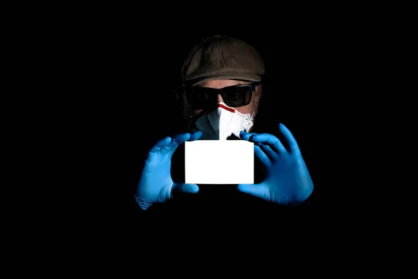 一名头戴防毒手套 头戴呼吸器的年长男子拿着一块空白白纸准备发短信 — 图库照片