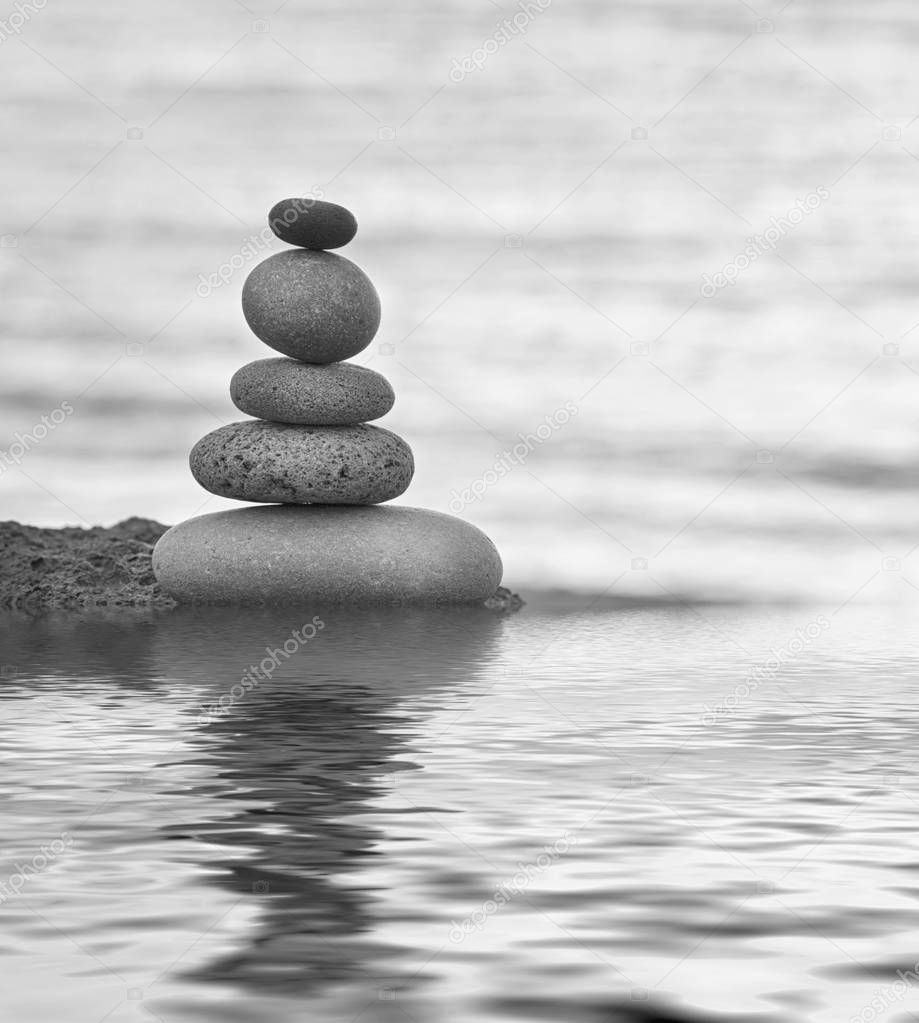 balanced pebble stack reflecting on calm water in black and white colors
