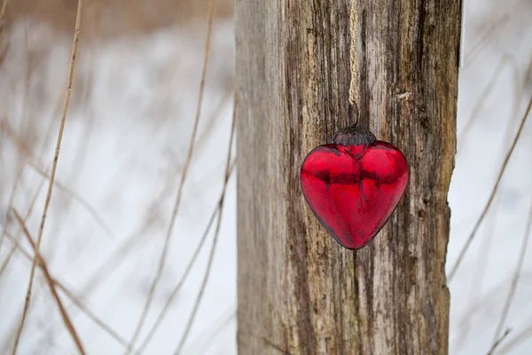 Rött glas hjärta hängande från ett inlägg — Stockfoto
