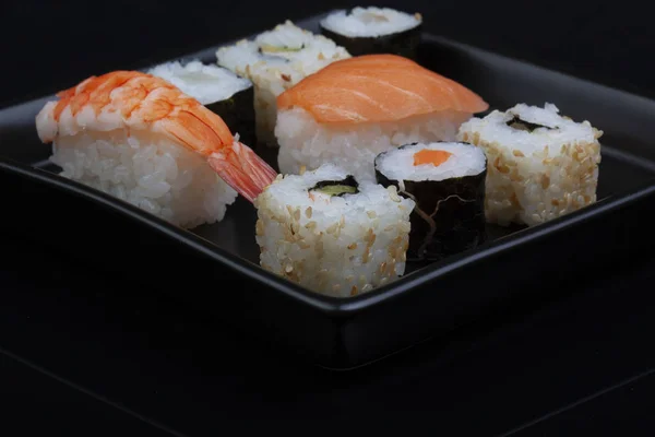 Sushi på fyrkantig platta över svart bakgrund — Stockfoto