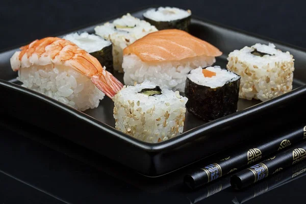 Sushi på fyrkantig platta över svart bakgrund — Stockfoto